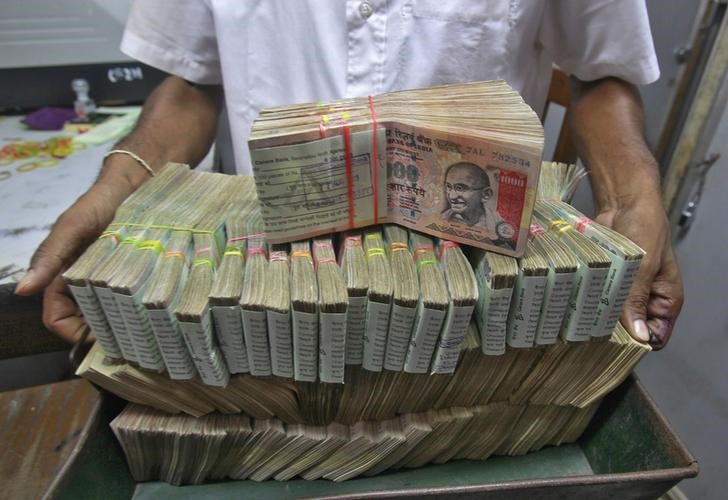 An employee poses with the bundles of Indian rupee notes inside a bank in Agartala
